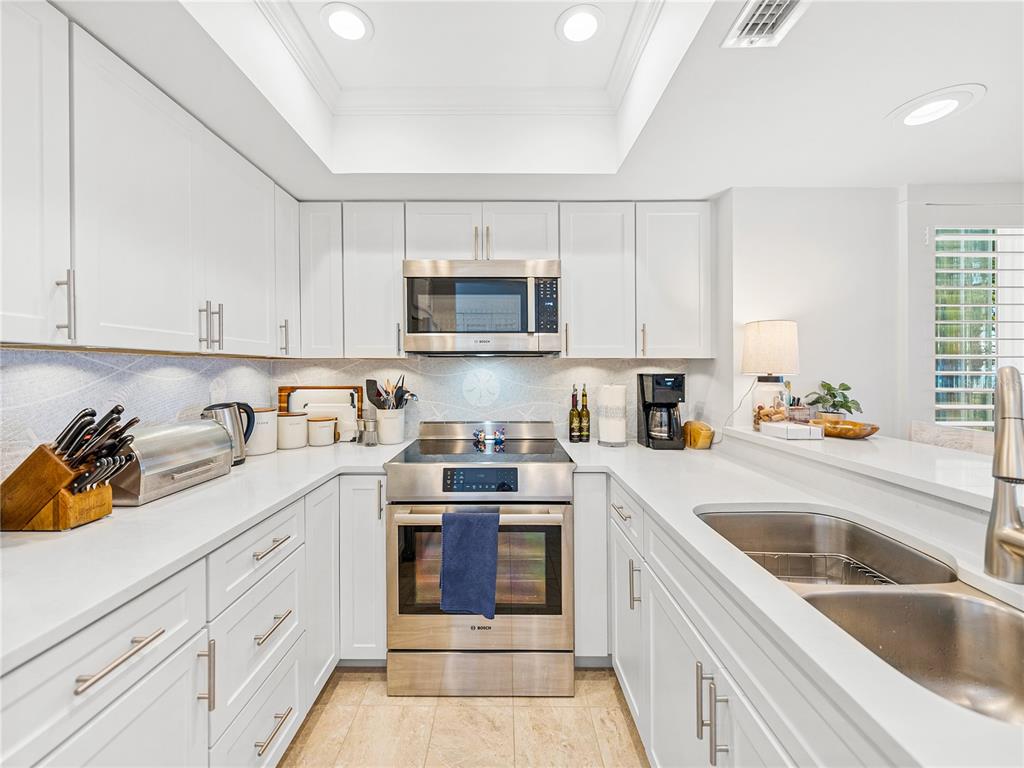 420 Gulf Boulevard, Unit 4 Boca Grande, FL 33921 - Photo 5 of 40 a kitchen with stainless steel appliances granite countertop a sink dishwasher stove and white cabinets with wooden floor