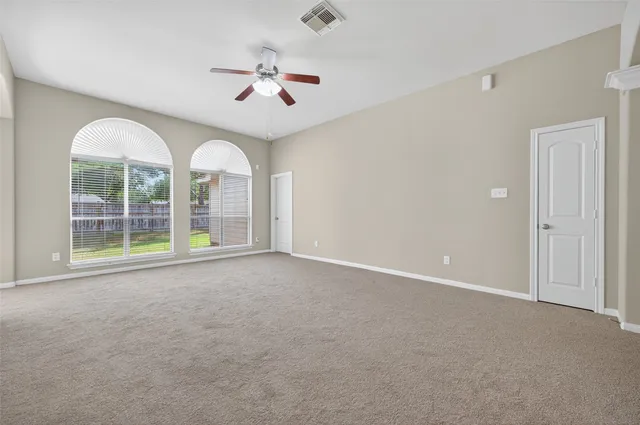 a view of a livingroom with a chandelier fan and windows