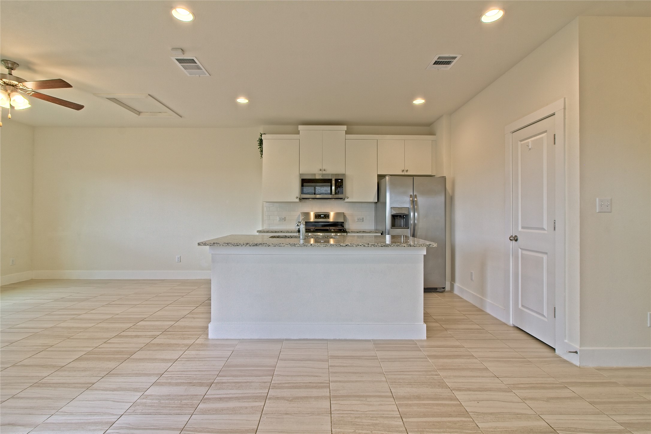 555 White Steppe Way Georgetown, TX 78626 - Photo 15 of 40 Kitchen featuring stainless steel appliances, white cabinetry, light stone countertops, a center island with sink, and a ceiling fan