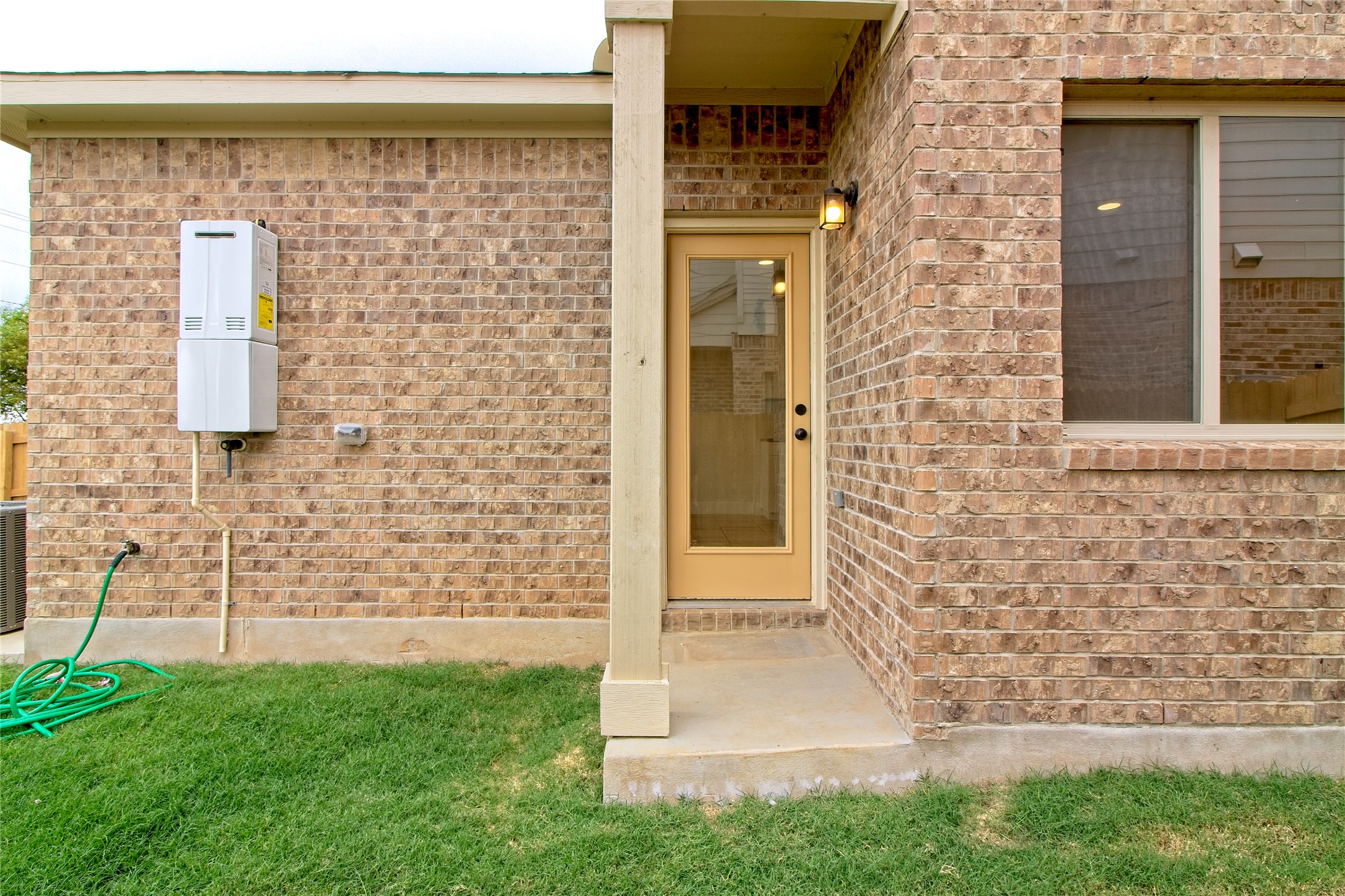 555 White Steppe Way Georgetown, TX 78626 - Photo 29 of 40 Entrance to property featuring brick siding, a yard, and water heater