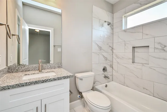 a bathroom with a granite countertop toilet sink and mirror