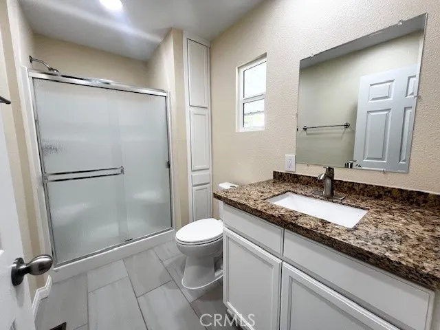 a bathroom with a granite countertop sink toilet and shower