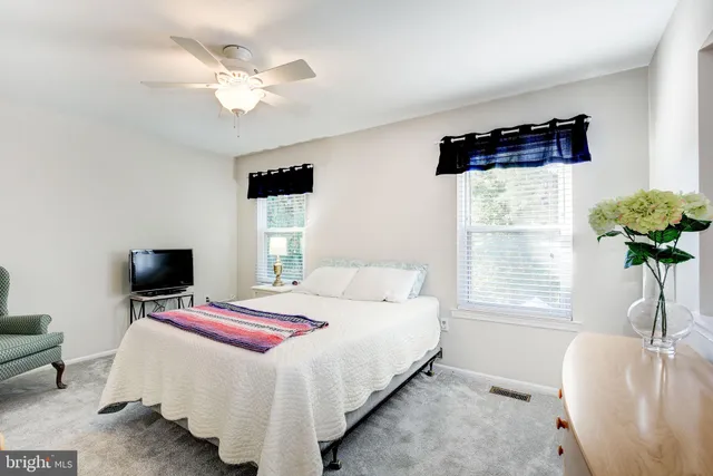 a bedroom with a bed a computer on the desk and a window