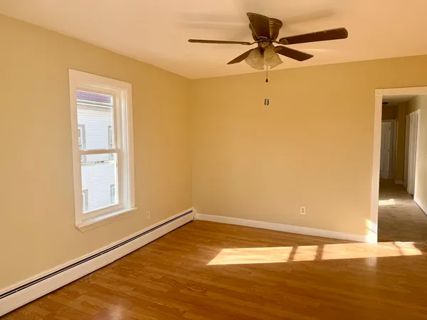 a view of a room with wooden floor and a ceiling fan