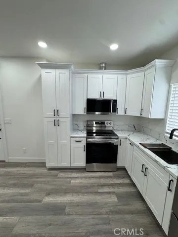 a kitchen with granite countertop white cabinets and stainless steel appliances