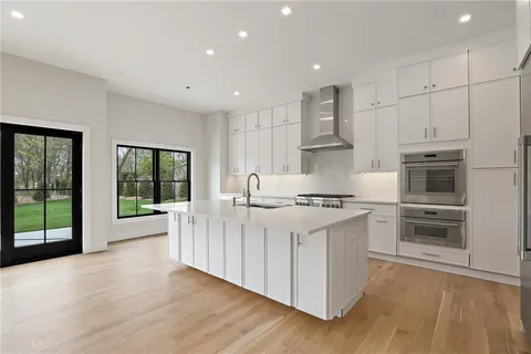 a kitchen with stainless steel appliances a white stove top oven and a refrigerator with wooden floor
