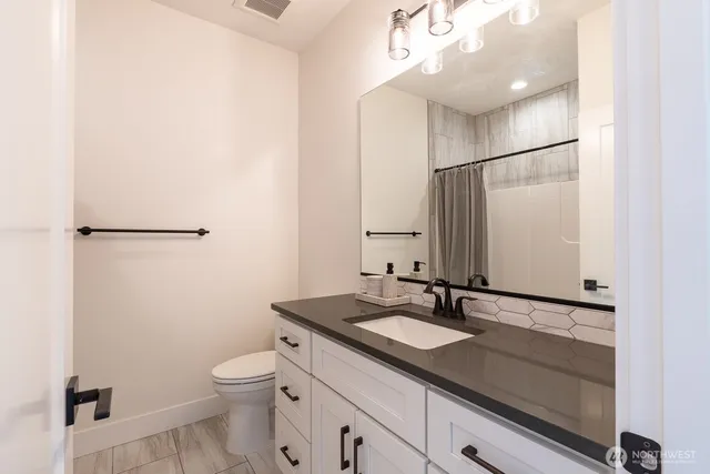 a bathroom with a sink a toilet a mirror and shower