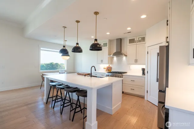 a kitchen with stainless steel appliances kitchen island granite countertop a sink a stove a refrigerator and island with wooden floor