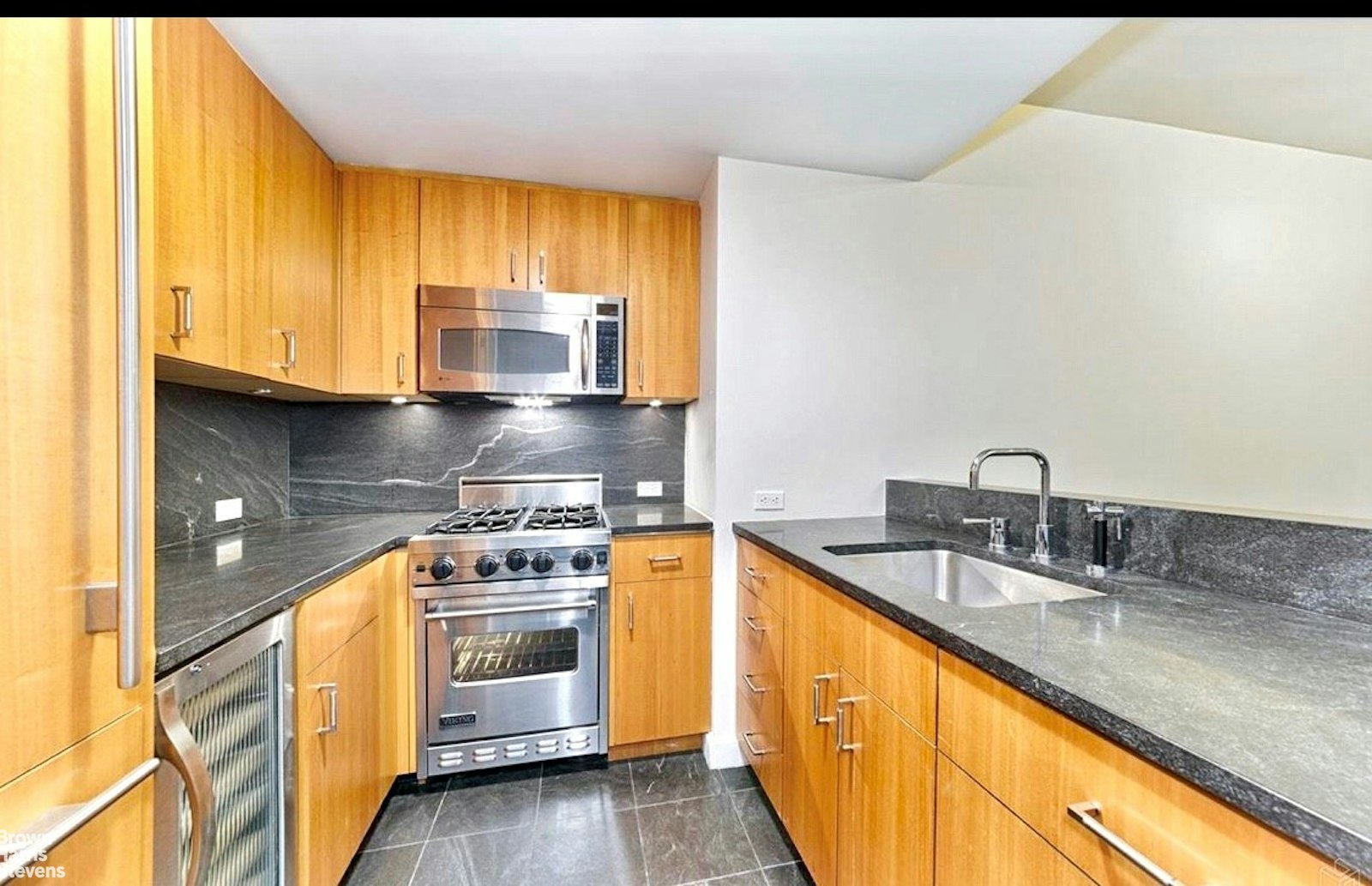 100 West 58th Street, Unit 5A Manhattan, NY 10019 - Photo 4 of 10 a kitchen with stainless steel appliances granite countertop a sink a stove and a microwave
