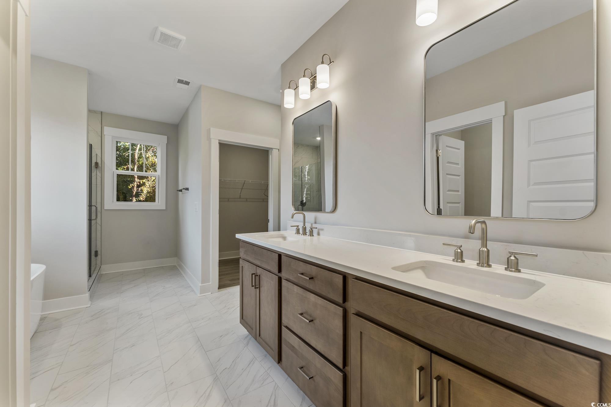 719 Daisy Bank Circle Georgetown, SC 29440 - Photo 21 of 33 Bathroom featuring a spacious closet, light marble finish flooring, double vanity, a shower stall, and a freestanding tub