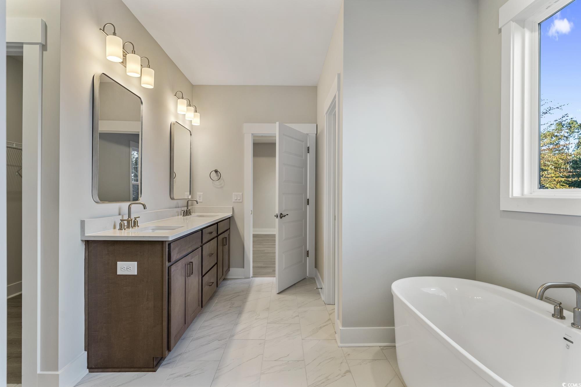 719 Daisy Bank Circle Georgetown, SC 29440 - Photo 22 of 33 Full bathroom featuring a walk in closet, double vanity, light marble finish flooring, and a freestanding bath