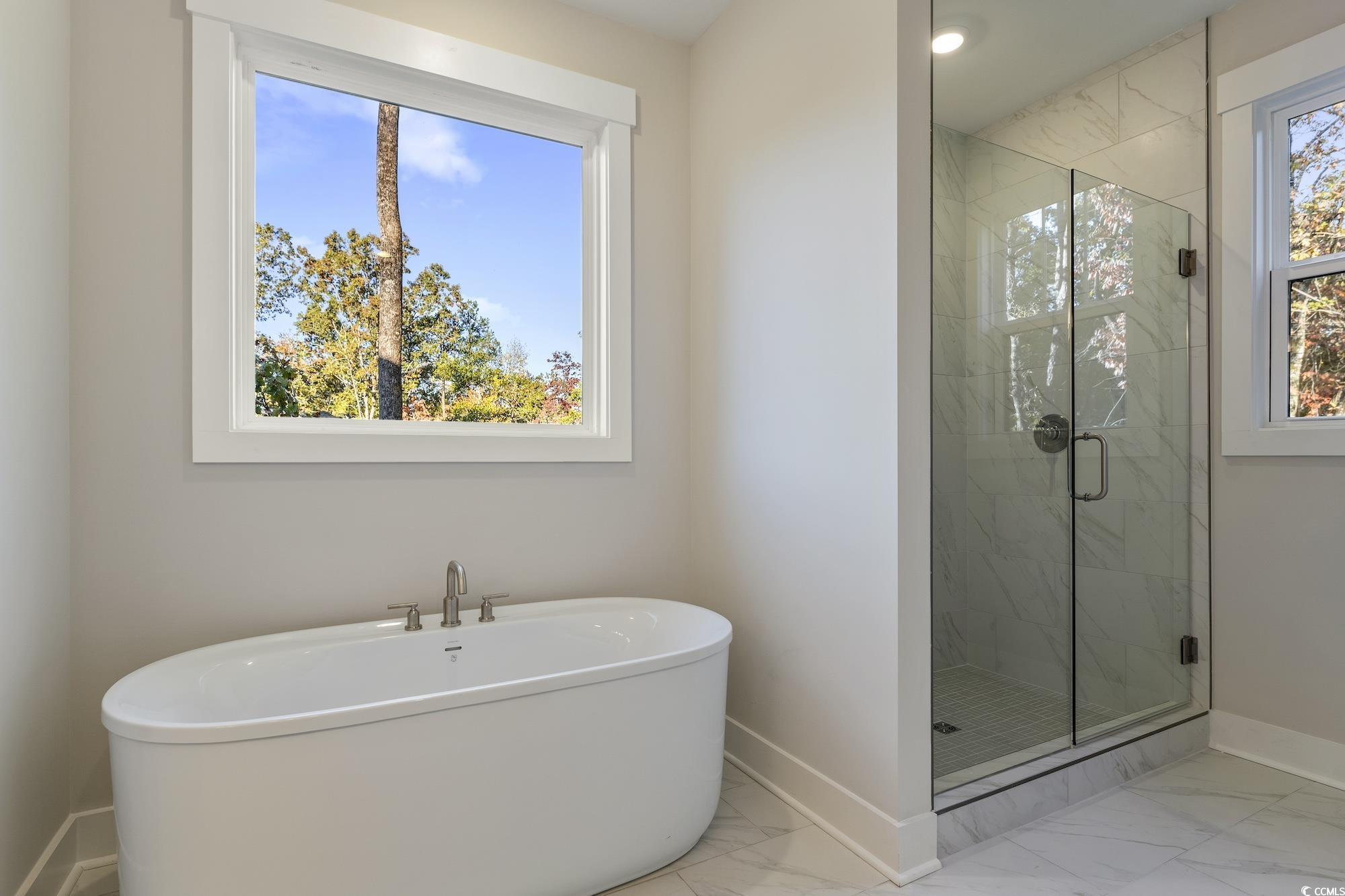 719 Daisy Bank Circle Georgetown, SC 29440 - Photo 23 of 33 Bathroom featuring marble look tile flooring, a marble finish shower, and a soaking tub