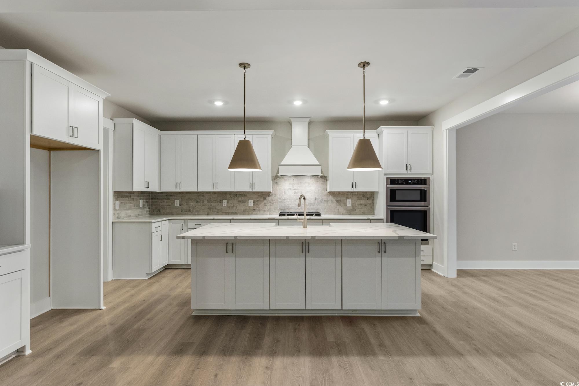 719 Daisy Bank Circle Georgetown, SC 29440 - Photo 10 of 33 Kitchen with decorative light fixtures, white cabinetry, a center island with sink, premium range hood, and light stone counters