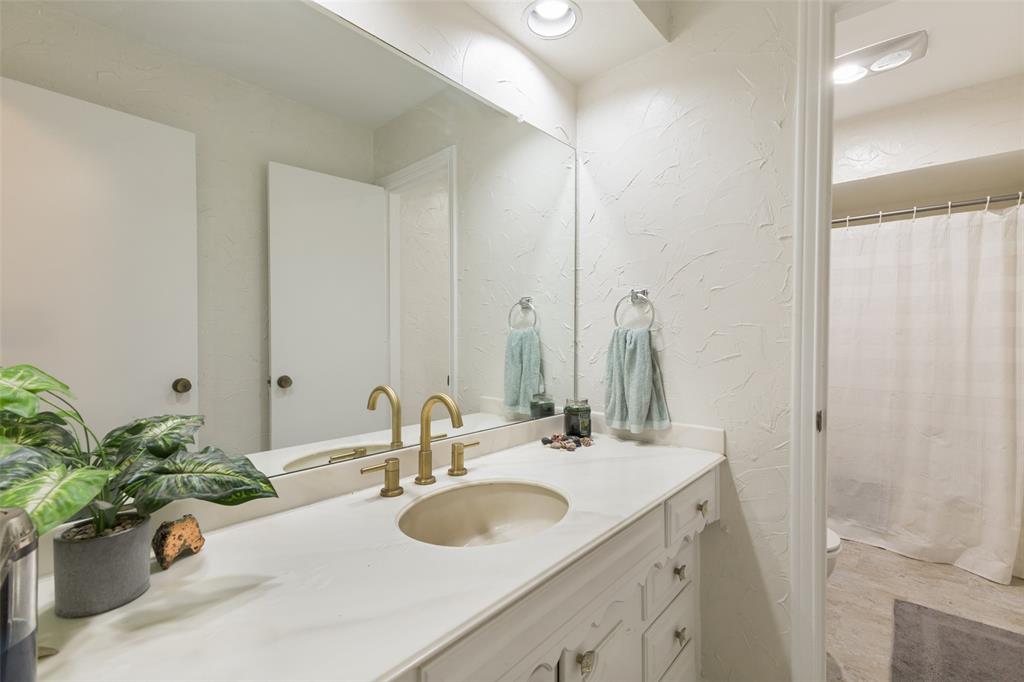 705 South Grove Road Richardson, TX 75081 - Photo 18 of 26 Bathroom vanity with a brass-finish faucet, an undermount sink, and a framed mirror