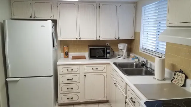 a kitchen with a refrigerator sink and cabinets