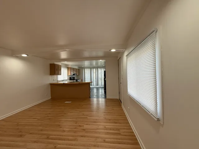 a view of a kitchen with kitchen island a sink wooden floor and a large window