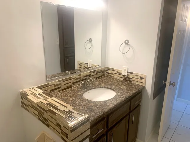 a bathroom with a granite countertop sink and a mirror
