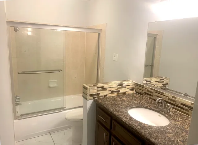 a bathroom with a granite countertop sink a toilet and shower