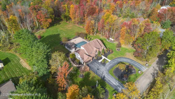 an aerial view of a house with a yard and large trees