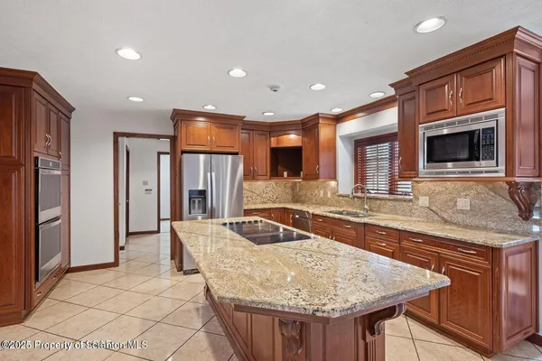 a kitchen with stainless steel appliances granite countertop a table chairs sink and cabinets