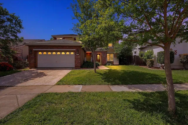 a sign that is sitting in front of a house with a big yard