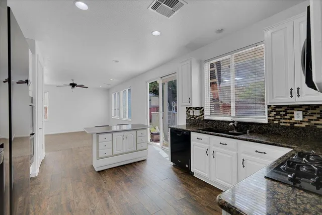 a kitchen with granite countertop a stove a sink and a refrigerator