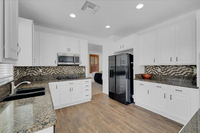 a kitchen with granite countertop a refrigerator and a sink