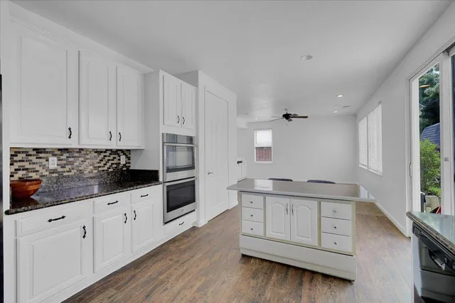 a kitchen with granite countertop white cabinets and window