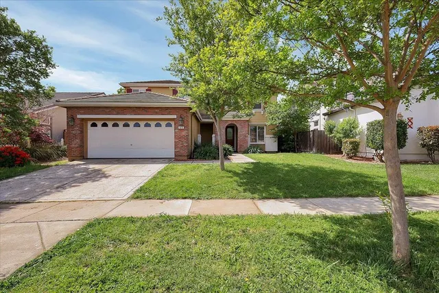 a view of a house with a yard and large tree