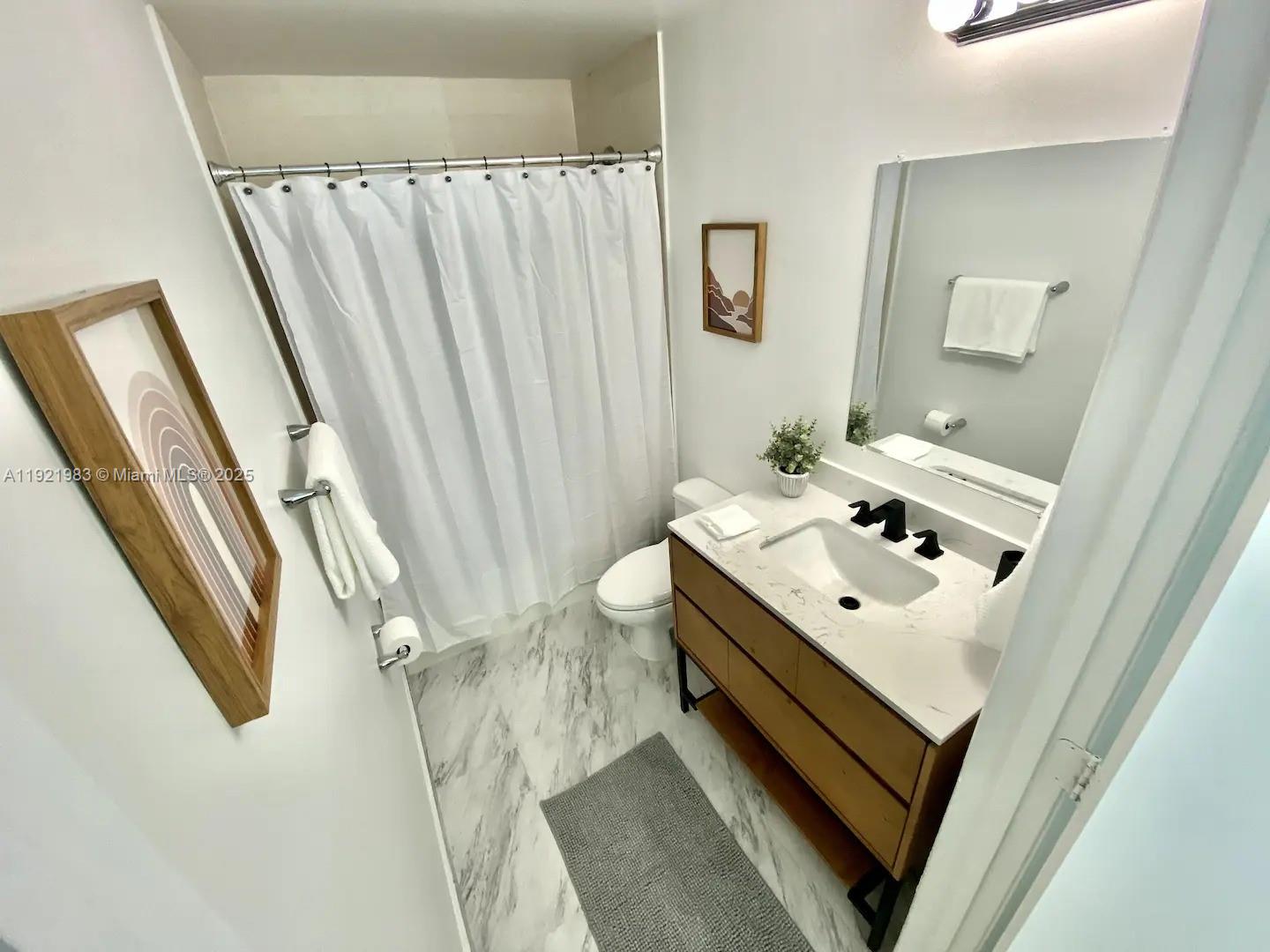 60 Southwest 13th Street, Unit 4414 Miami, FL 33130 - Photo 4 of 22 a bathroom with a sink a toilet and a mirror