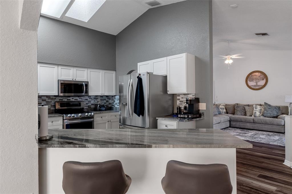 10918 Midland Bridge Road Hudson, FL 34667 - Photo 13 of 42 a kitchen with stainless steel appliances granite countertop a stove top oven a sink and a microwave