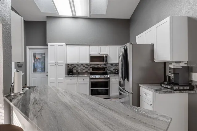 a kitchen with granite countertop a refrigerator stove and oven