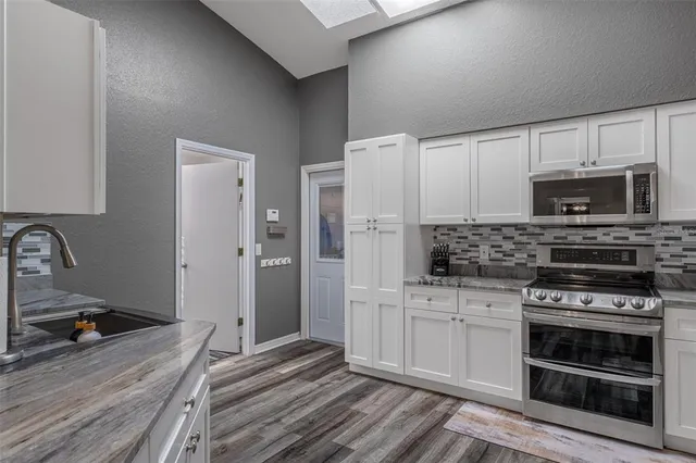 a kitchen with white cabinets and stainless steel appliances