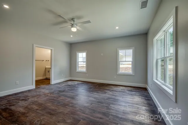a view of an empty room with a window and wooden floor