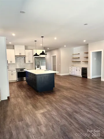 a large kitchen with kitchen island a stove a sink dishwasher and a refrigerator with wooden floor