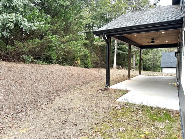 a backyard of a house with table and chairs under an umbrella