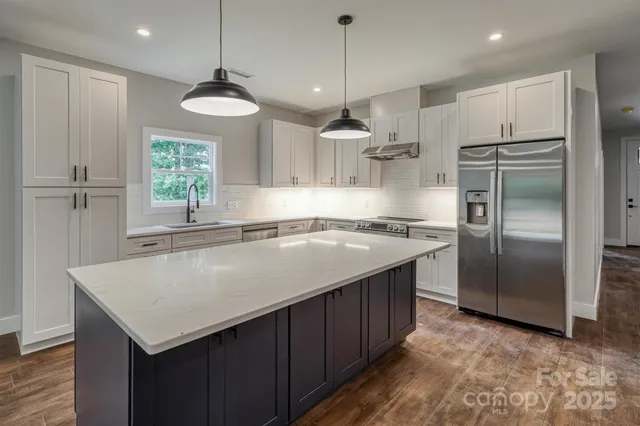 a kitchen with kitchen island a counter space refrigerator and windows