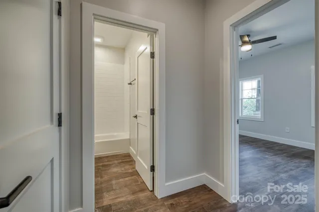 a view of a hallway with a glass door and a bathroom in it