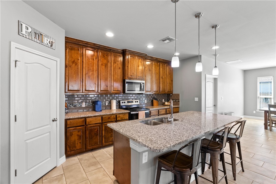 1815 Monterey Bay Drive Portland, TX 78374 - Photo 8 of 38 a kitchen with a table chairs refrigerator and microwave