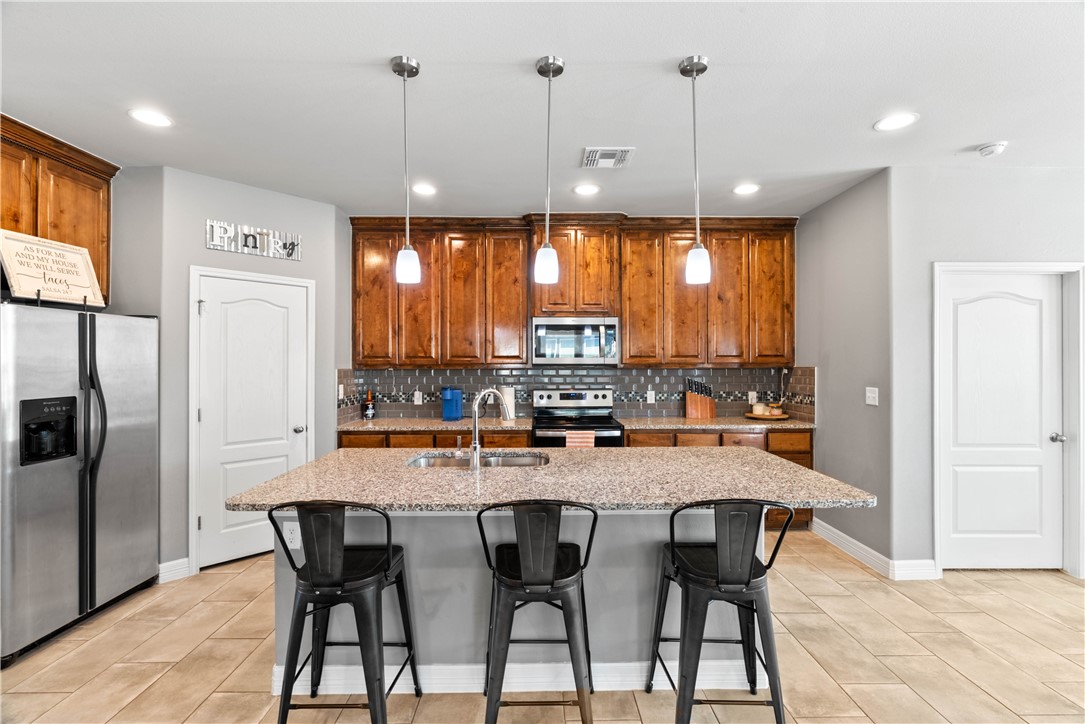 1815 Monterey Bay Drive Portland, TX 78374 - Photo 9 of 38 a kitchen with stainless steel appliances granite countertop a kitchen island a stove a table and chairs