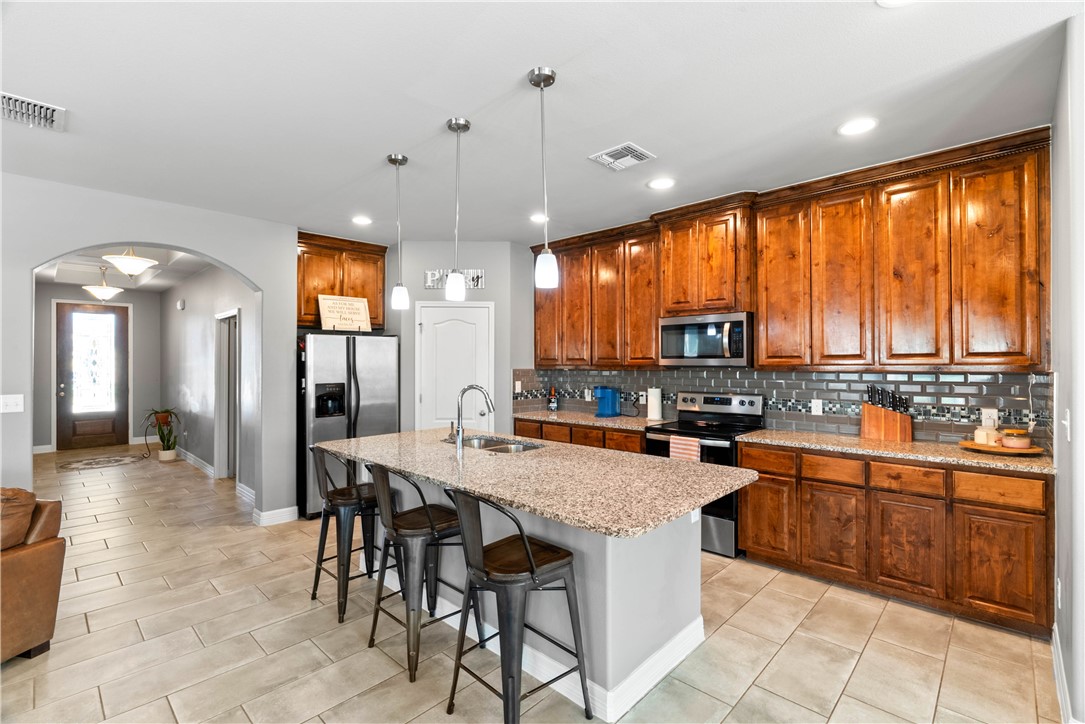 1815 Monterey Bay Drive Portland, TX 78374 - Photo 10 of 38 a kitchen with granite countertop a table chairs sink and wooden cabinets