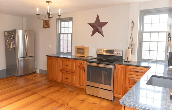 a kitchen with stainless steel appliances granite countertop a refrigerator a stove a sink and a window
