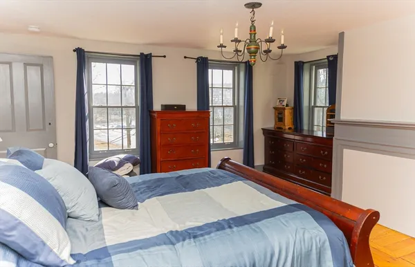 a bedroom with a large bed a chandelier and dresser