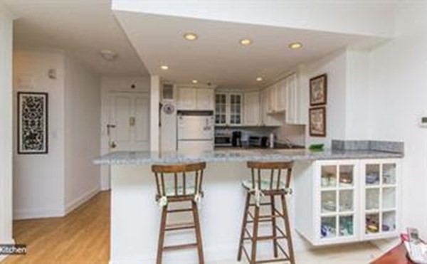 151 Tremont Street, Unit 7B Boston, MA 02111 - Photo 1 of 14 a open kitchen with stainless steel appliances granite countertop a stove top oven a sink a dining table and chairs with wooden floor