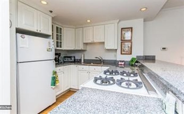 151 Tremont Street, Unit 7B Boston, MA 02111 - Photo 2 of 14 a kitchen with a refrigerator stove and white cabinets