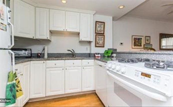 151 Tremont Street, Unit 7B Boston, MA 02111 - Photo 3 of 14 a kitchen with granite countertop a sink and white cabinets