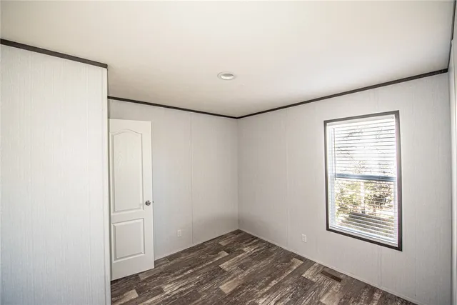 a view of an empty room with closet and a window
