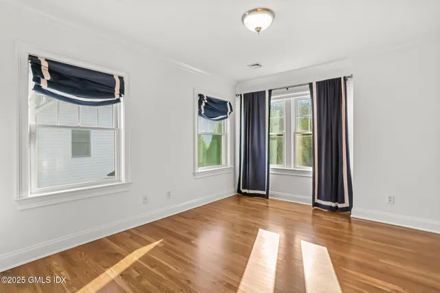 a view of an empty room with wooden floor and white walls