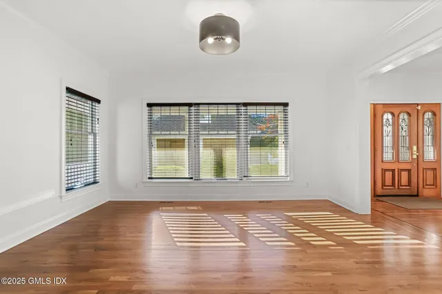 a view of an empty room with wooden floor and a window