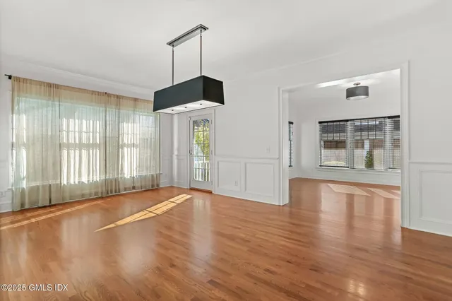 a view of an empty room with window and wooden floor